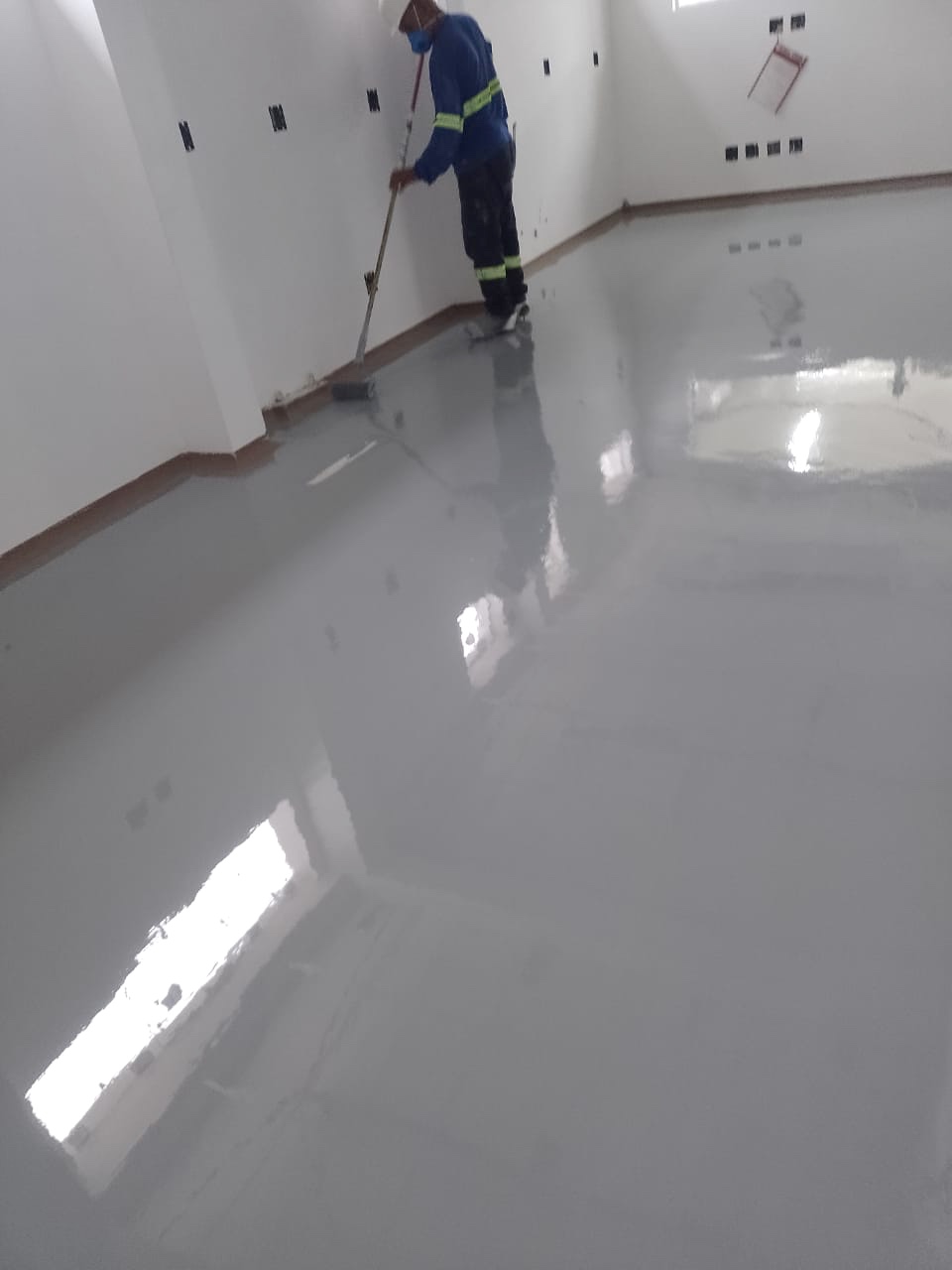 Profissional durante a aplicação de revestimento cinza no piso