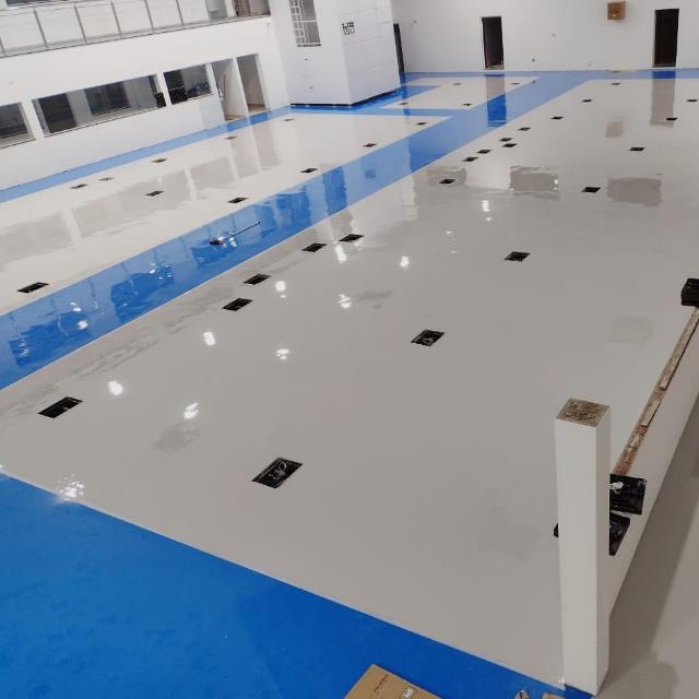 Ambiente industrial com piso cinza e faixas azuis