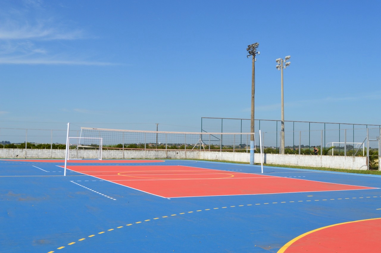 Quadra poliesportiva externa azul e vermelha com demarcações